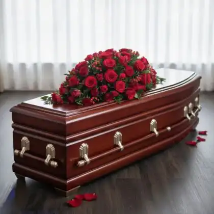A lush arrangement of deep red roses and greenery designed as elegant funeral casket sprays for a memorial service.