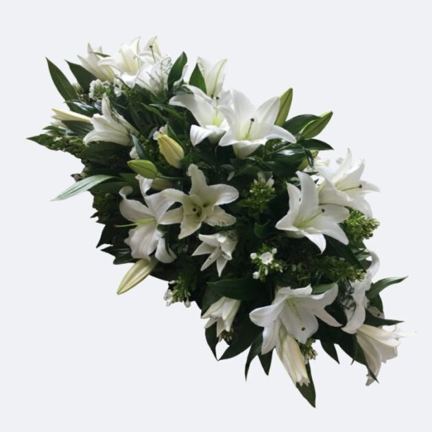 A large and elegant White Lily Casket Spray arranged with lush greenery for a funeral tribute.
