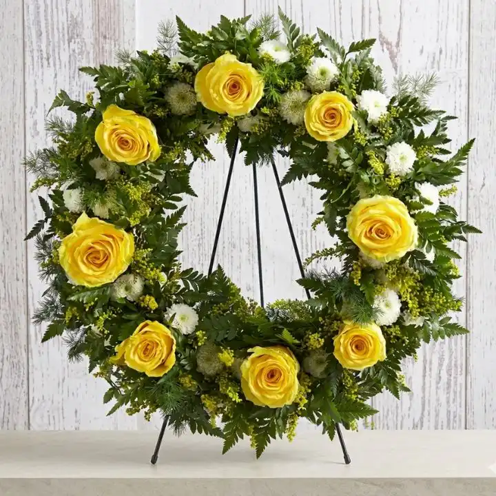 Sunny Serenity Fresh Funeral Wreath 1 A circular arrangement of fresh flower funeral wreaths featuring vibrant yellow roses and white lilies on a clean background.