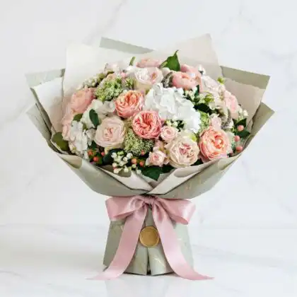 A hand-tied white hydrangea and pink rose bouquet styled with seasonal greenery for a soft aesthetic.