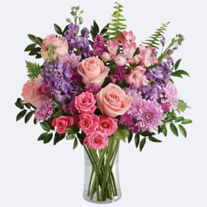 A professional roses and gerbera arrangement in a woven basket featuring pink blossoms and white lilies.