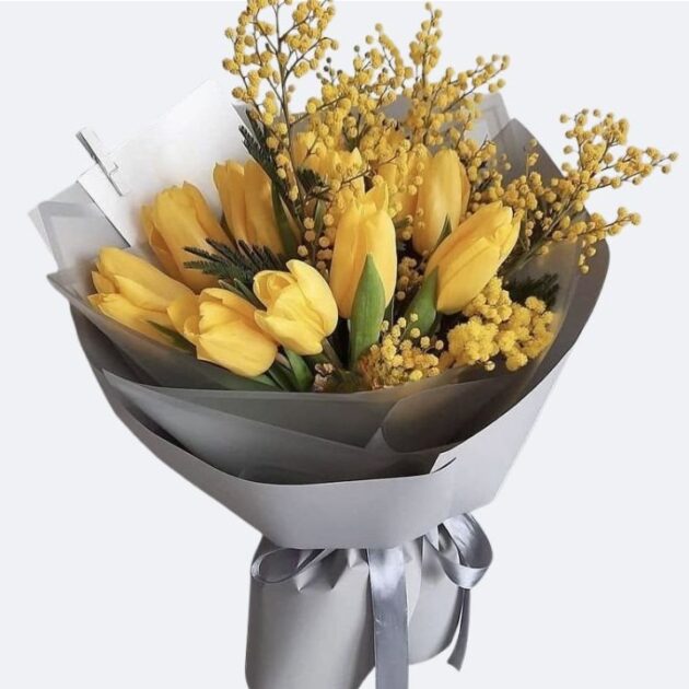 Vibrant Yellow Tulips and Mimosa Hand-Tied Bouquet 1 A stunning Yellow Tulips Bouquet accented with golden mimosa and elegant silver gift wrapping.