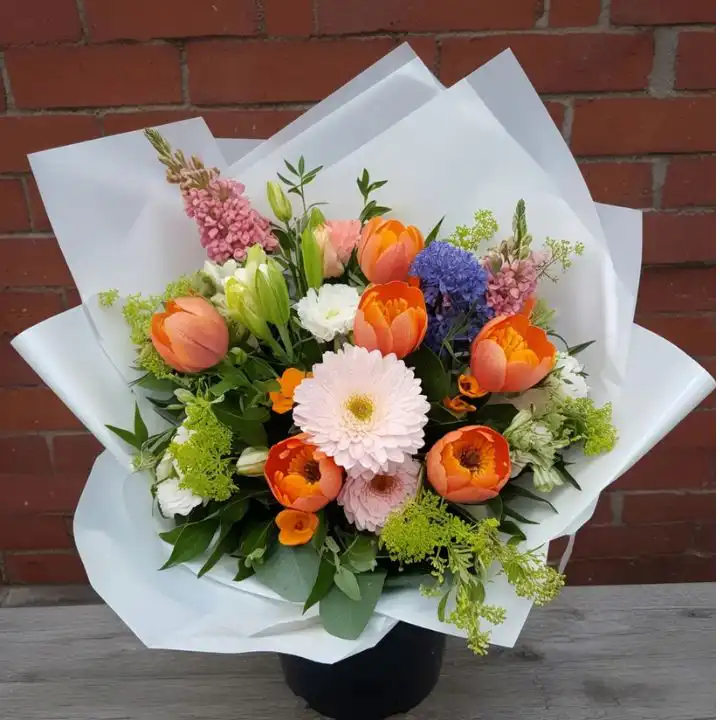 Vibrant Gerbera and Tulip Bouquets 1 Hand-tied Gerbera and Tulip Bouquets featuring bright orange tulips and soft pink gerberas in white wrap.
