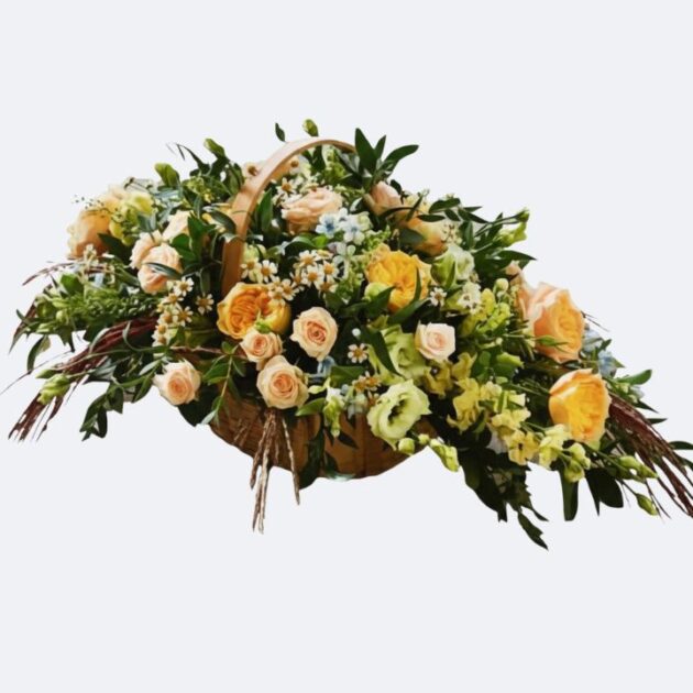 Large, elegant Basket Flower Arrangement for Funeral featuring soft peach roses, vibrant yellow blooms, and fresh green foliage presented in a natural wicker container.