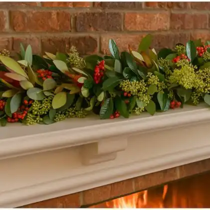 Premium artificial Christmas garland for fireplace mantel, featuring vibrant red berries and mixed evergreen leaves over a white mantle.