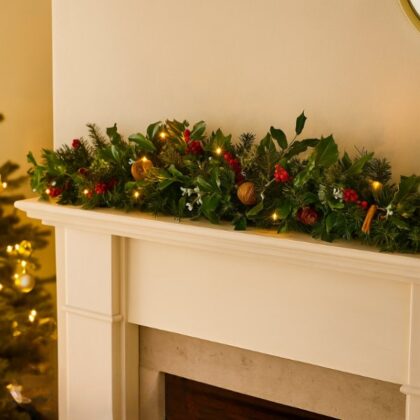 A festive and realistic Christmas garland with lights for fireplace decor, featuring holly, berries, pine, and walnuts.