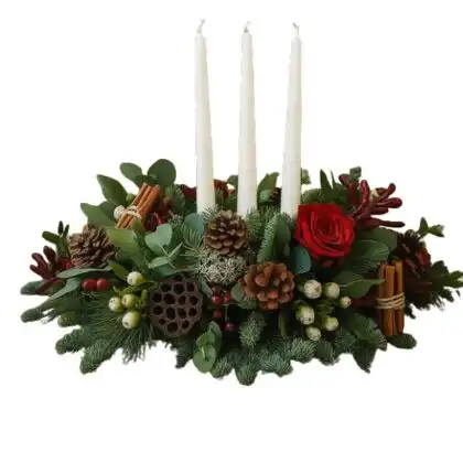 A festive arrangement of Christmas table centrepieces with candles, featuring red flowers, holly, and ribbon accents.