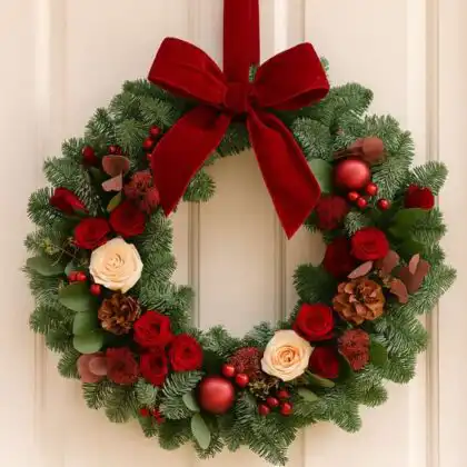 A classic, handcrafted Traditional Christmas Door Wreath featuring pinecones, red berries, and a vibrant velvet bow, perfect for holiday decor.