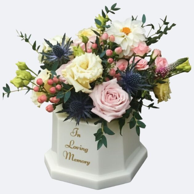In Loving Memory Flower Vase with Blush Rose and Thistle 1 In Loving Memory Flower Vase featuring a graceful assortment of blush pink roses, creamy yellow blooms, striking blue thistles, and complementary greenery, displayed in a white keepsake memorial urn.