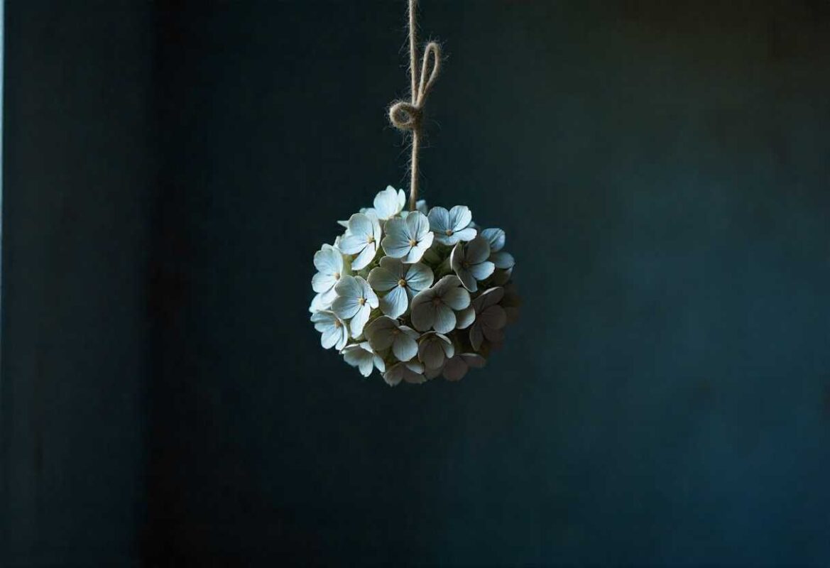 A creative hanging decoration made from small, light-colored dried Hydrangea florets tied with rustic twine, showcasing another method of How to Dry Hydrangea Flowers.